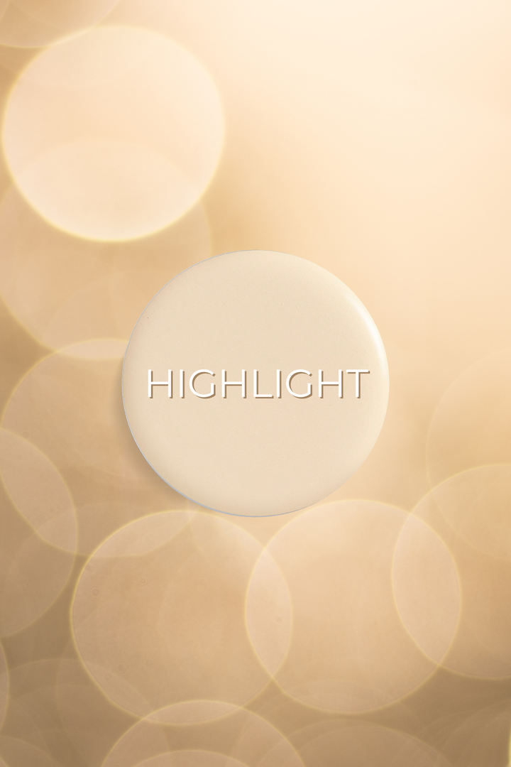 Round compact of shimmering gold highlighter powder on a blurred background.